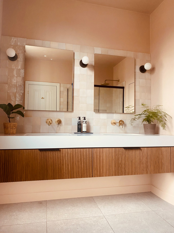 Cette image montre une grande salle de bain principale et grise et rose minimaliste en bois foncé avec un placard à porte affleurante, un espace douche bain, WC suspendus, un carrelage rose, un mur rose, un sol en carrelage de porcelaine, un lavabo suspendu, un sol gris, une cabine de douche à porte coulissante, un plan de toilette blanc, meuble double vasque et meuble-lavabo encastré.