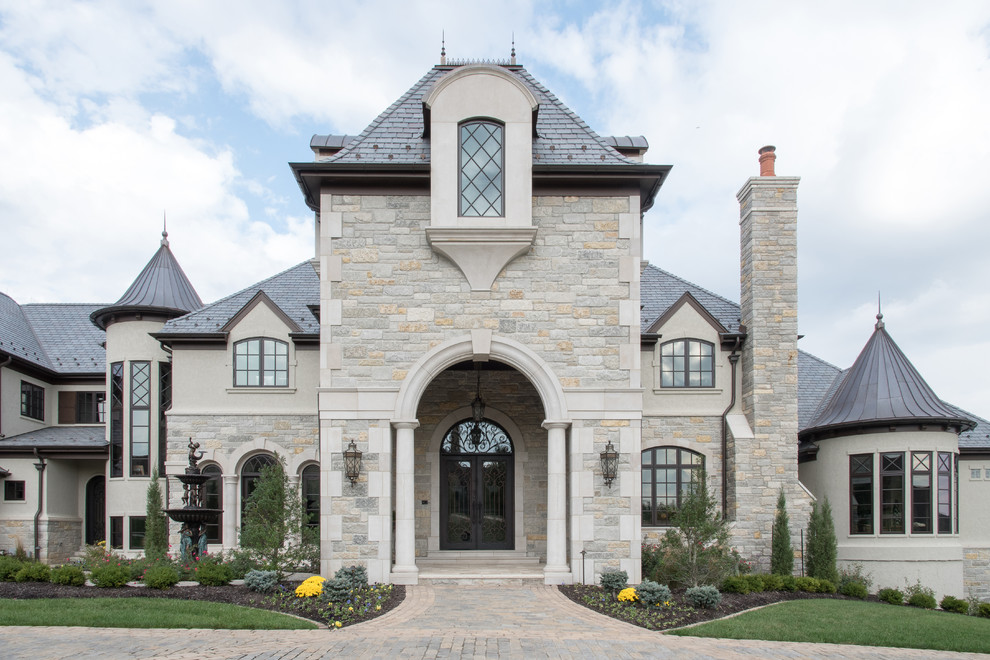 Inspiration for a traditional two-storey beige house exterior in St Louis with stone veneer, a hip roof and a shingle roof.