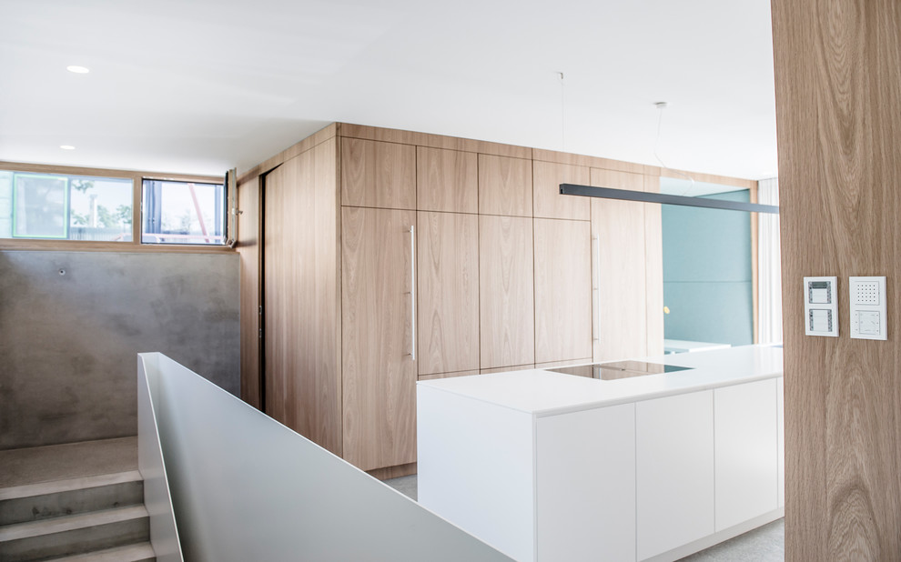 Design ideas for a mid-sized modern open plan kitchen in Stuttgart with flat-panel cabinets, white cabinets, panelled appliances, concrete floors, with island and grey floor.