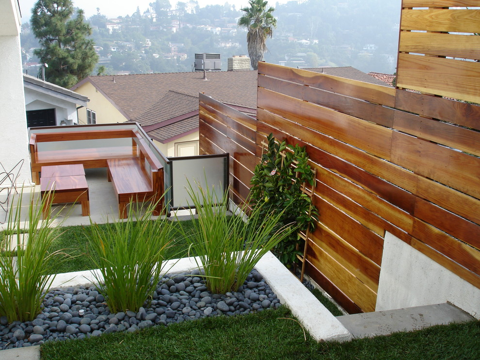 This is an example of a mid-sized contemporary sloped partial sun formal garden in Los Angeles with a retaining wall and gravel.
