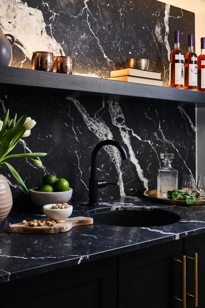 This is an example of a transitional home bar in Toronto with an undermount sink, marble benchtops, black splashback, marble splashback and black benchtop.