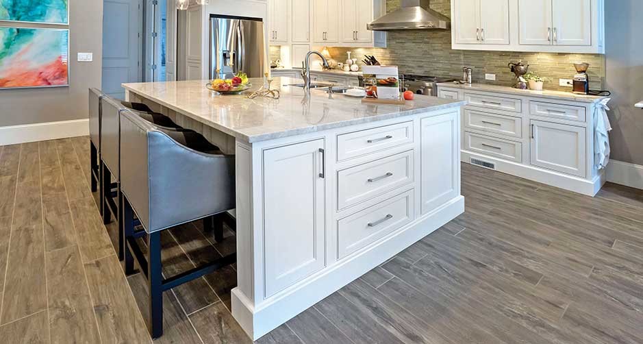 Enclosed kitchen - mid-sized transitional l-shaped medium tone wood floor enclosed kitchen idea in Boston with an undermount sink, beaded inset cabinets, white cabinets, marble countertops, white backsplash, subway tile backsplash, stainless steel appliances and an island