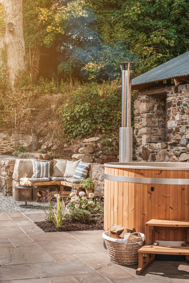 Medium sized rural back above ground hot tub in Cornwall with natural stone paving.
