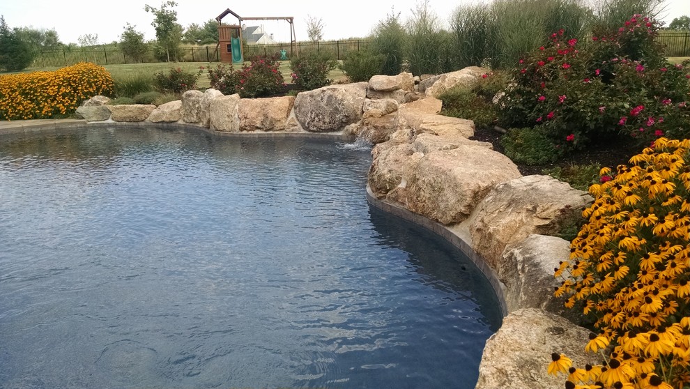 Example of a large mountain style backyard custom-shaped and stamped concrete pool fountain design in New York