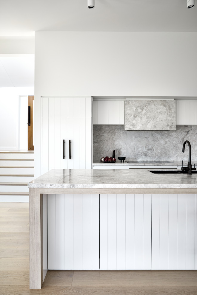 Inspiration for a large contemporary galley kitchen in Sydney with an undermount sink, flat-panel cabinets, white cabinets, grey splashback, stone slab splashback, panelled appliances, medium hardwood floors, with island, brown floor and grey benchtop.