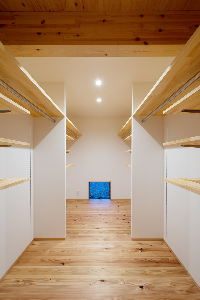 Immagine di una cabina armadio unisex scandinava di medie dimensioni con nessun'anta, pavimento in legno massello medio, pavimento marrone e soffitto in carta da parati
