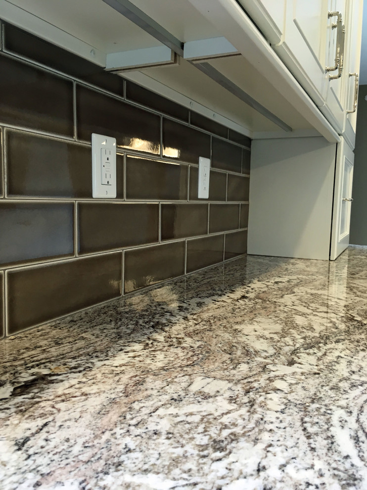 Large transitional l-shaped vinyl floor and beige floor eat-in kitchen photo with a double-bowl sink, recessed-panel cabinets, white cabinets, granite countertops, brown backsplash, ceramic backsplash, stainless steel appliances and an island