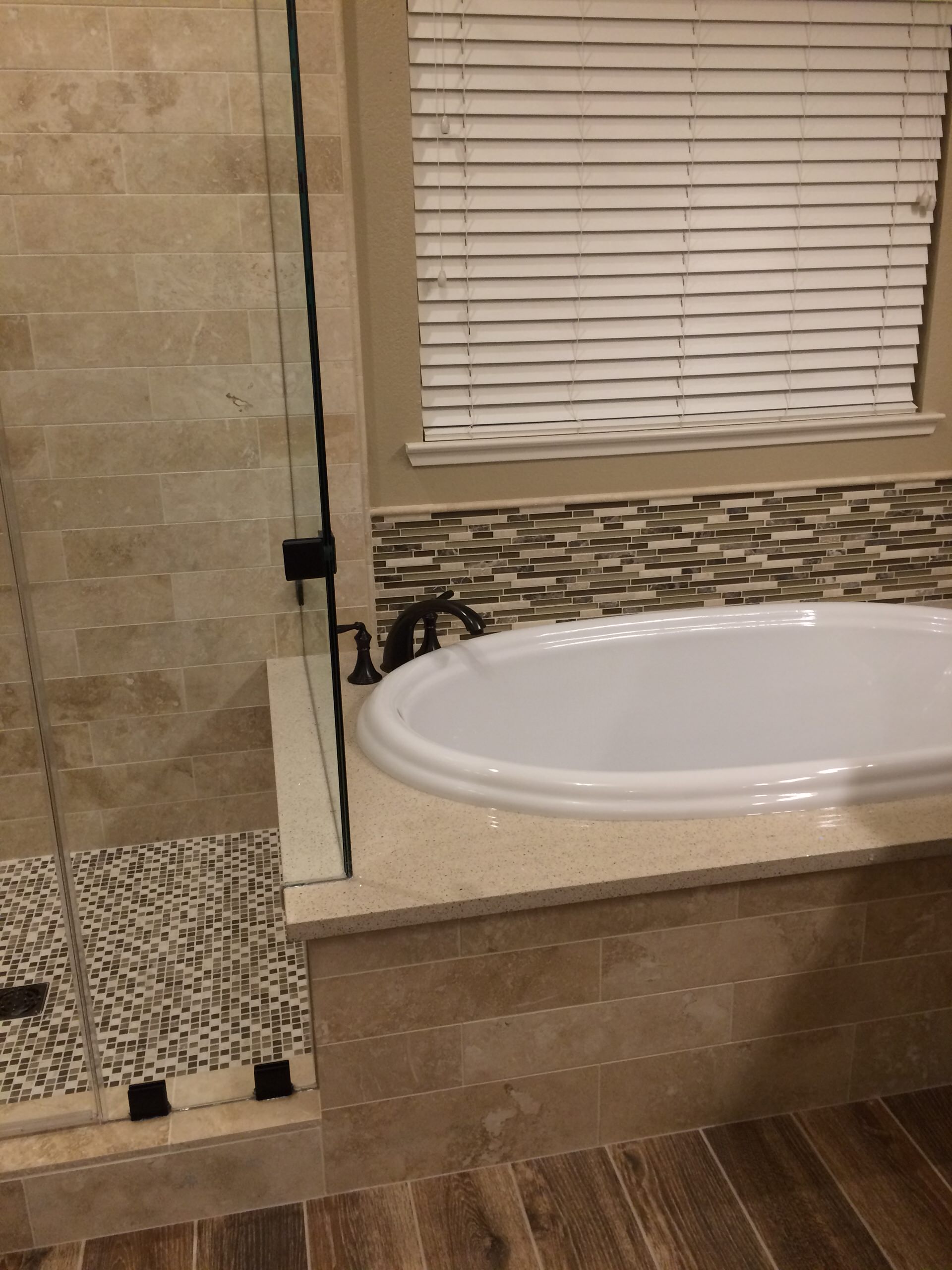 Tub & shower transition in warm tone tile and quartz slab.