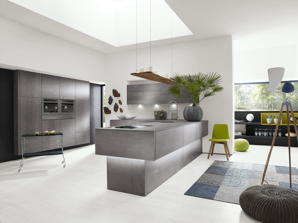 Design ideas for a mid-sized modern l-shaped eat-in kitchen in Miami with an integrated sink, flat-panel cabinets, grey cabinets, concrete benchtops, stainless steel appliances, laminate floors, a peninsula, grey splashback and glass sheet splashback.