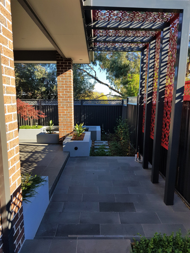 Design ideas for a mid-sized modern backyard partial sun formal garden for summer in Melbourne with with flowerbed and natural stone pavers.
