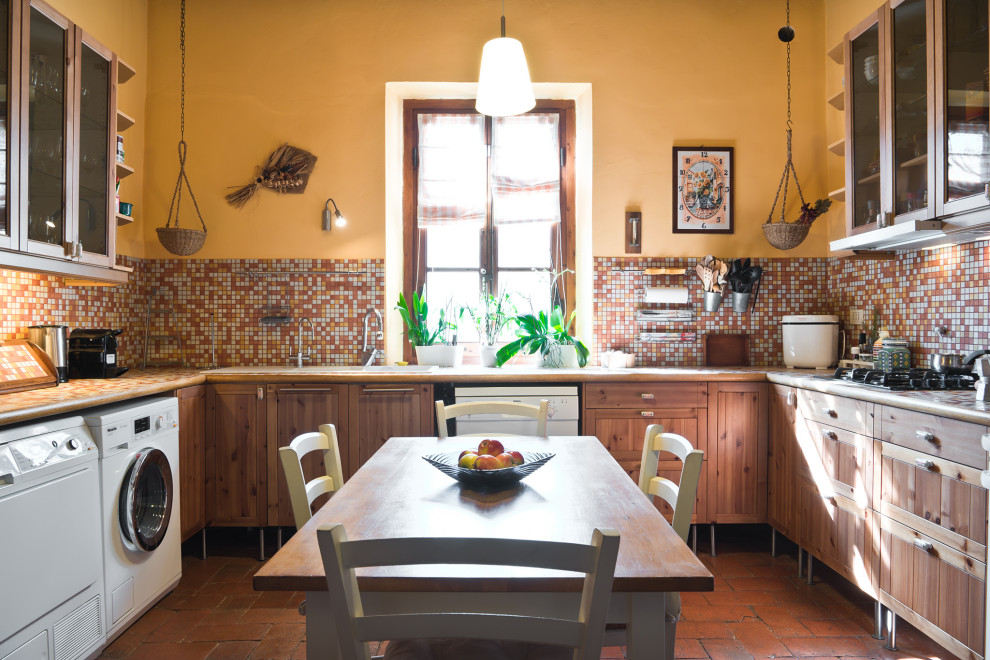 Inspiration for a mid-sized mediterranean u-shaped eat-in kitchen in Florence with a drop-in sink, medium wood cabinets, multi-coloured splashback, mosaic tile splashback, white appliances, terra-cotta floors, orange floor, shaker cabinets and multi-coloured benchtop.
