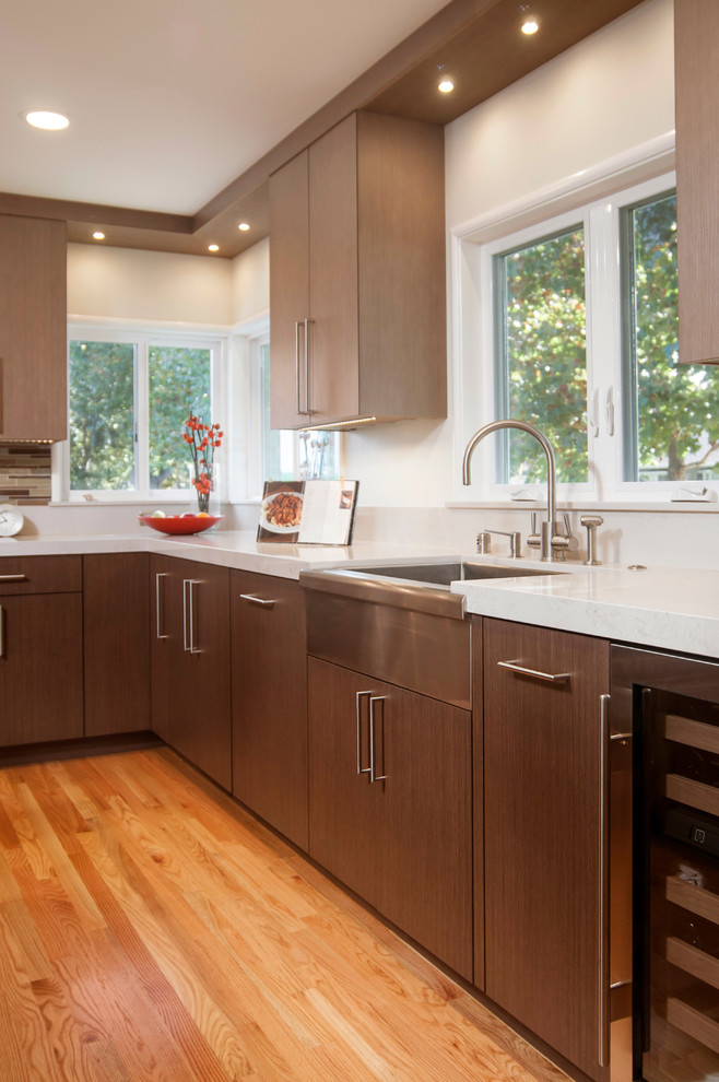Mid-sized contemporary kitchen in San Francisco with a farmhouse sink, flat-panel cabinets, medium wood cabinets, quartz benchtops, multi-coloured splashback, stainless steel appliances, medium hardwood floors and with island.