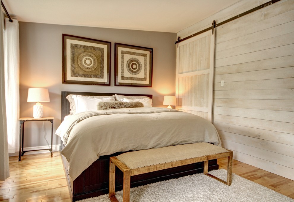 This is an example of a mid-sized country master bedroom in Montreal with grey walls and light hardwood floors.