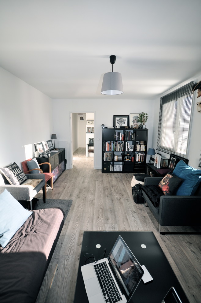 This is an example of a mid-sized contemporary enclosed family room in Lyon with a library, white walls, light hardwood floors and grey floor.