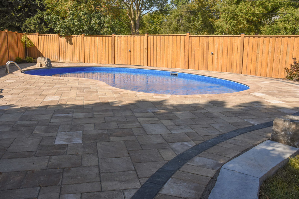 Foto di una grande piscina minimal a "C" dietro casa con pavimentazioni in cemento