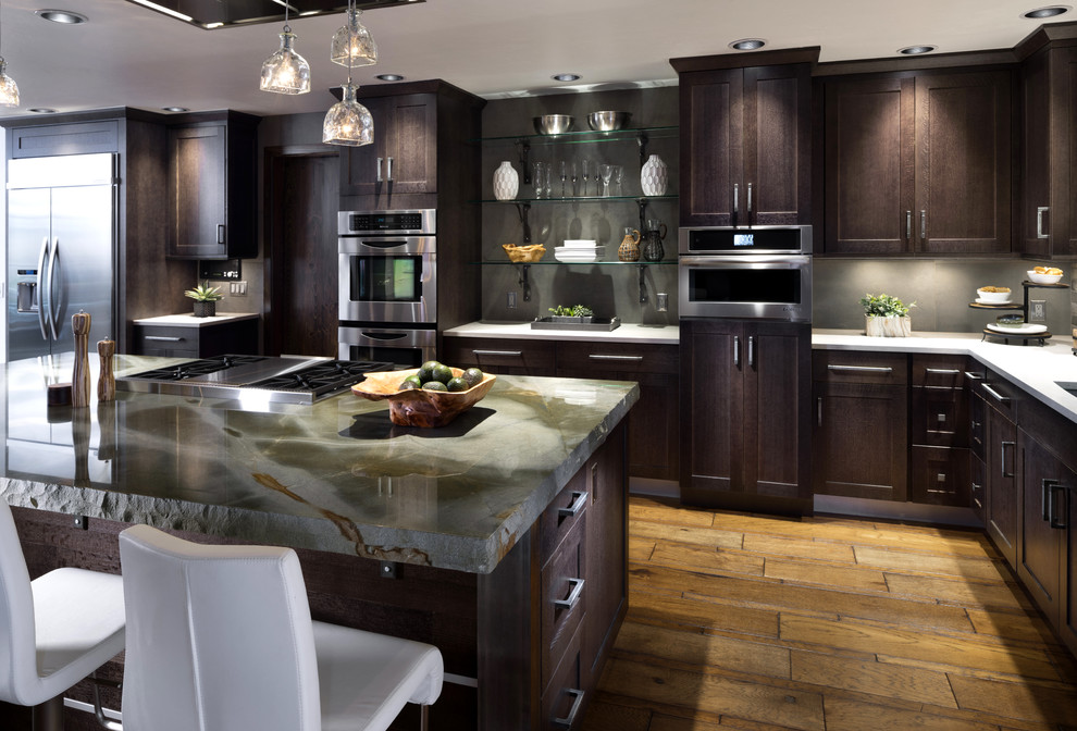 Inspiration for a mid-sized contemporary open plan kitchen in Oklahoma City with a single-bowl sink, shaker cabinets, dark wood cabinets, quartzite benchtops, grey splashback, brick splashback, stainless steel appliances, medium hardwood floors, with island and brown floor.