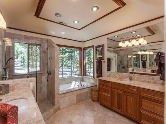 Photo of a mid-sized traditional master bathroom in Sacramento with an undermount sink, raised-panel cabinets, dark wood cabinets, marble benchtops, a hot tub, a corner shower, a one-piece toilet, beige tile, stone tile, beige walls and travertine floors.
