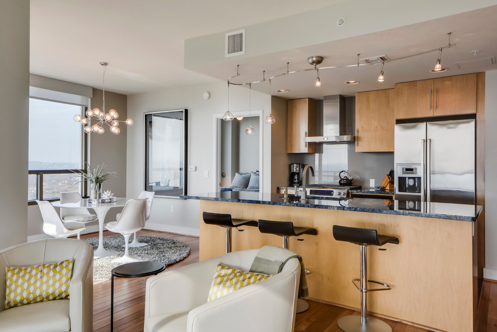 Small transitional galley light wood floor open concept kitchen photo in Austin with a double-bowl sink, flat-panel cabinets, light wood cabinets, granite countertops, gray backsplash, porcelain backsplash, stainless steel appliances and an island