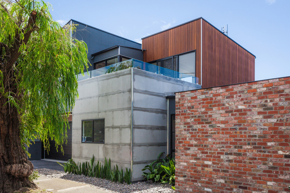 This is an example of a large industrial three-storey grey house exterior in Newcastle - Maitland with concrete fiberboard siding, a flat roof and a metal roof.