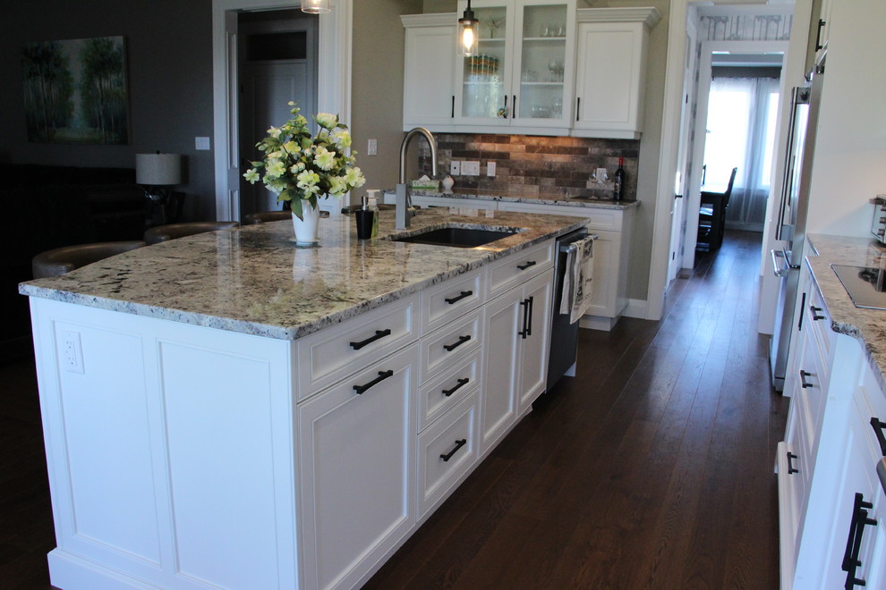 Example of a large transitional l-shaped dark wood floor and brown floor eat-in kitchen design in Toronto with an undermount sink, shaker cabinets, white cabinets, granite countertops, multicolored backsplash, subway tile backsplash, stainless steel appliances and an island