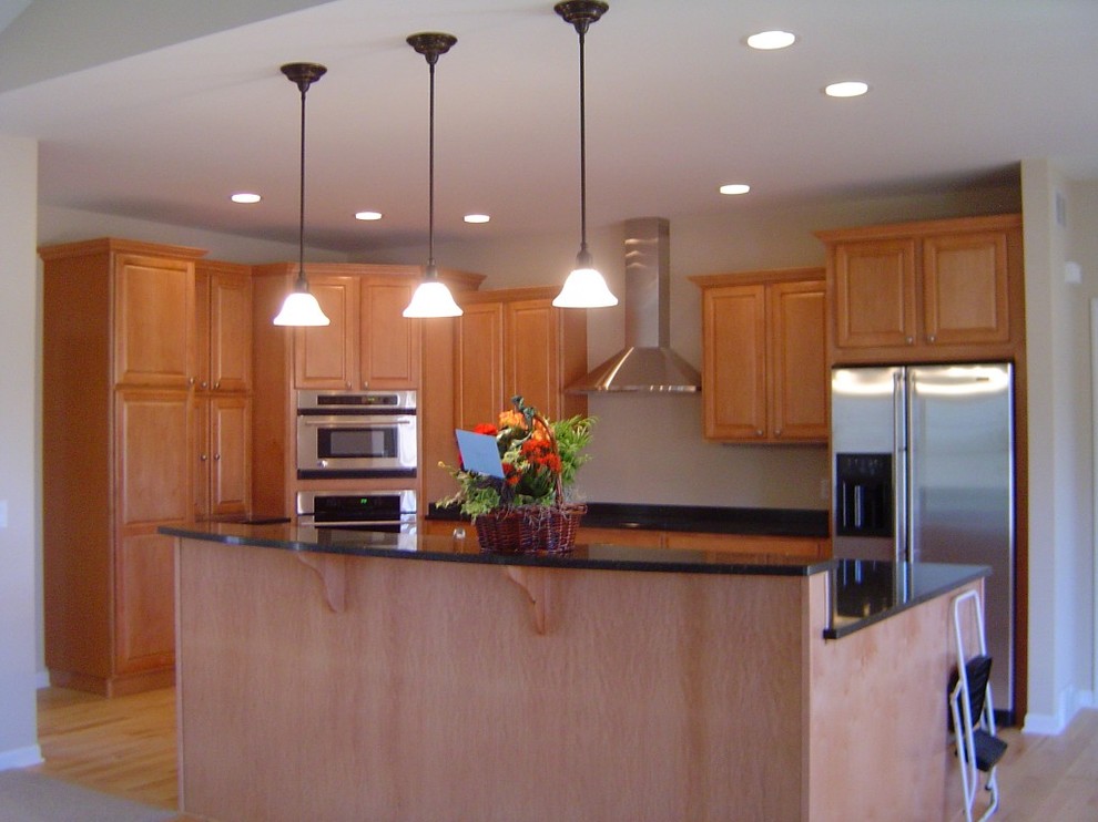 Inspiration for a mid-sized transitional l-shaped light wood floor eat-in kitchen remodel with a double-bowl sink, raised-panel cabinets, medium tone wood cabinets, quartz countertops, stainless steel appliances and an island