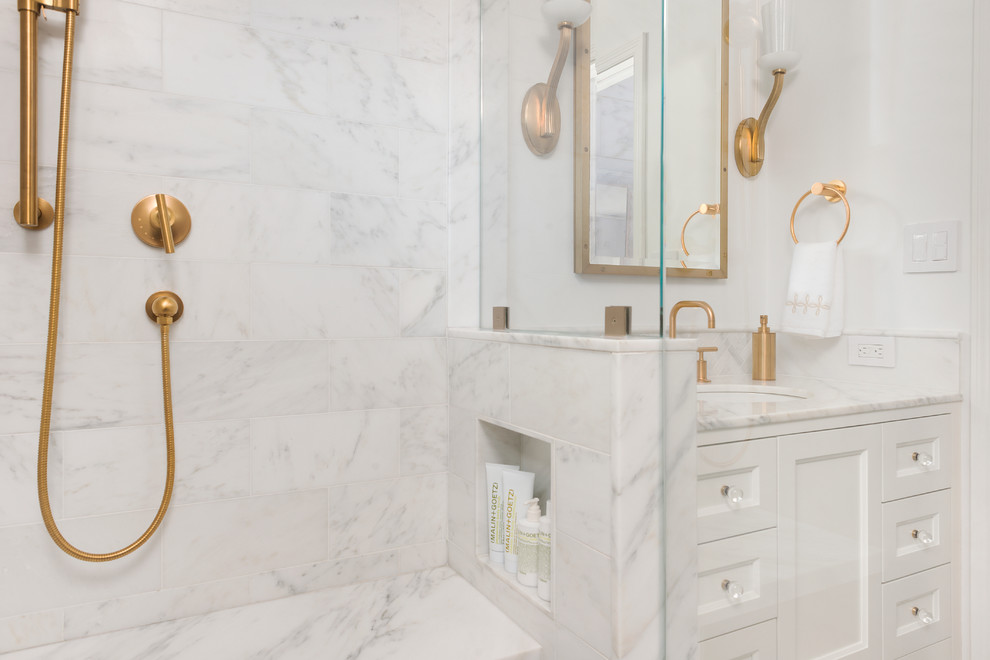 This is an example of a small transitional master bathroom in Boston with shaker cabinets, a wall-mount toilet, white tile, stone tile, white walls, mosaic tile floors, an undermount sink, marble benchtops, white cabinets, an alcove shower, a hinged shower door and white floor.