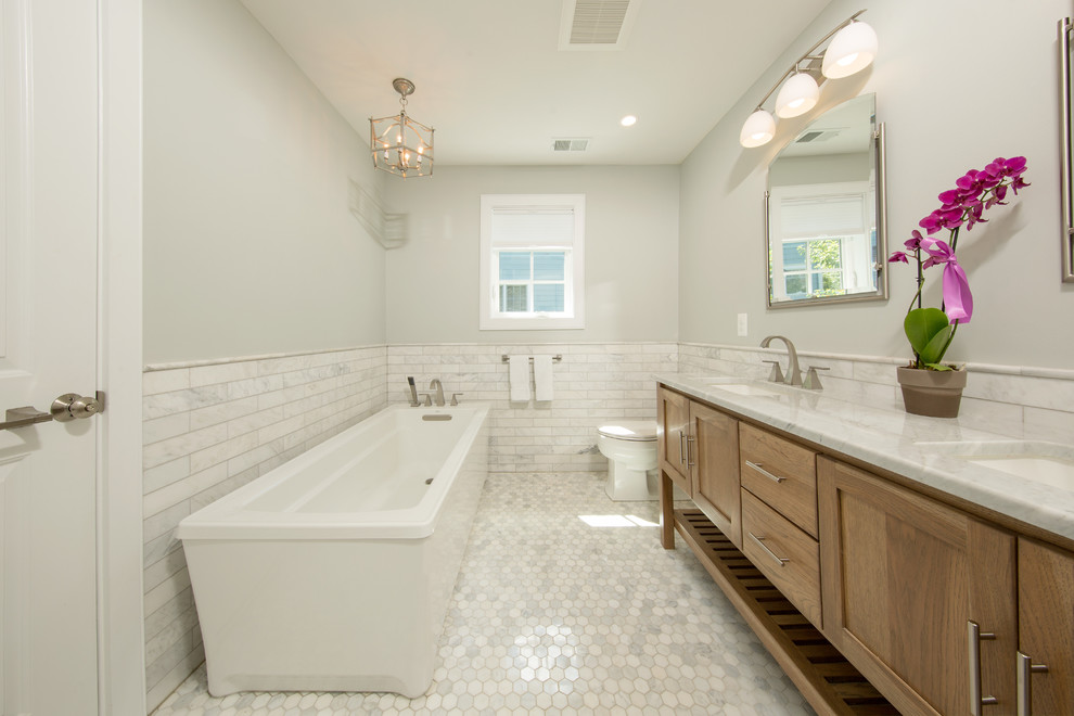 Design ideas for a mid-sized transitional master bathroom in DC Metro with recessed-panel cabinets, medium wood cabinets, a freestanding tub, an alcove shower, a two-piece toilet, white tile, marble, white walls, marble floors, an undermount sink, marble benchtops, white floor and a hinged shower door.