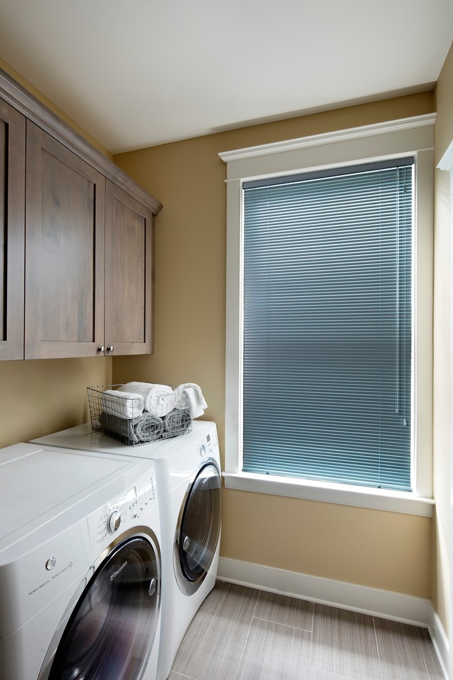 Design ideas for a small transitional galley dedicated laundry room in Baltimore with shaker cabinets, medium wood cabinets, beige walls, ceramic floors, a side-by-side washer and dryer and brown floor.
