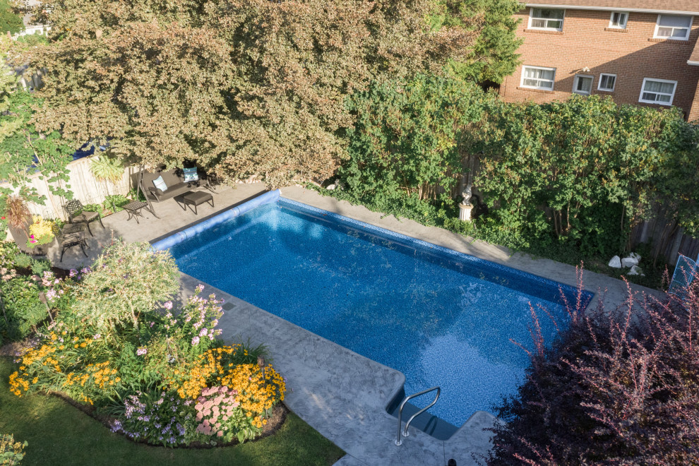 This is an example of a mid-sized modern backyard rectangular pool in Toronto with with a pool and stamped concrete.