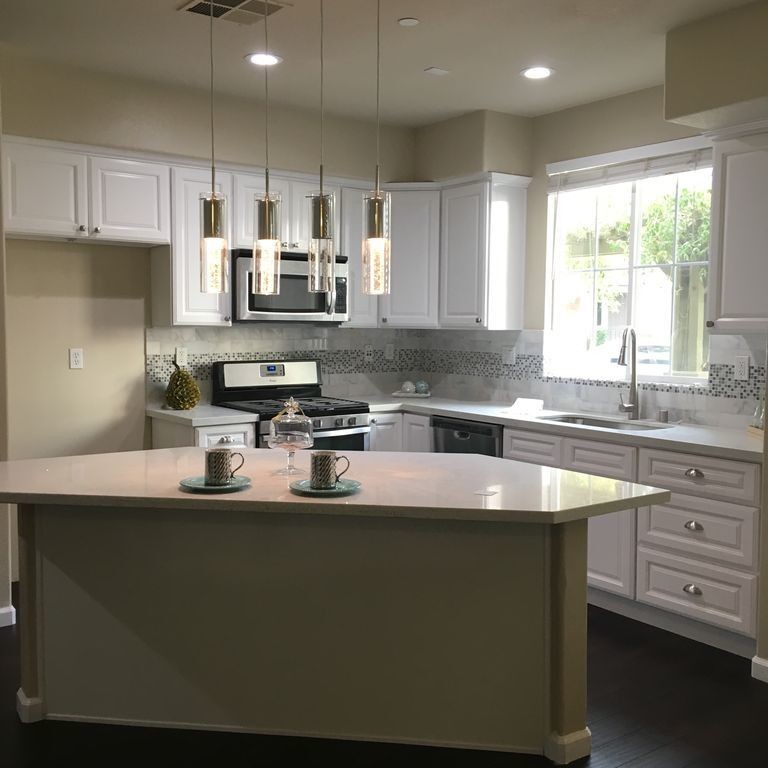 Example of a mid-sized transitional l-shaped dark wood floor kitchen design in Orange County with raised-panel cabinets, white cabinets, multicolored backsplash, mosaic tile backsplash, stainless steel appliances and an island