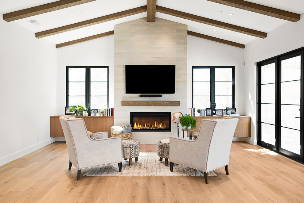 This is an example of a mid-sized country enclosed family room in San Francisco with white walls, light hardwood floors, a standard fireplace, a tile fireplace surround, a wall-mounted tv and brown floor.