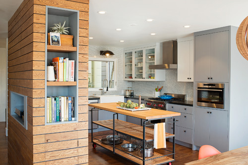 Industrial-style rolling kitchen island with butcher-block work surface and open metal shelves, paired with grey kitchen cabinets—shows a practical countertop choice