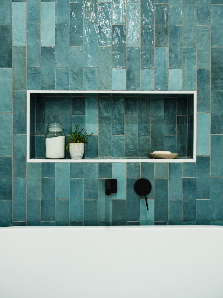 This is an example of a mid-sized midcentury master bathroom in Melbourne with flat-panel cabinets, medium wood cabinets, an open shower, a wall-mount toilet, blue tile, porcelain tile, white walls, porcelain floors, an integrated sink, solid surface benchtops, grey floor, an open shower, white benchtops, a single vanity and a floating vanity.