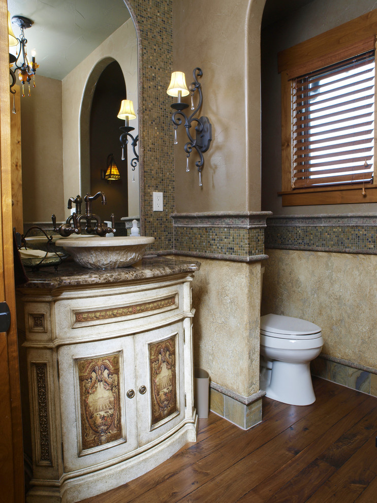 Inspiration for a mid-sized mediterranean bathroom in Denver with a vessel sink, furniture-like cabinets, beige cabinets, granite benchtops, a two-piece toilet, green tile, brown walls and medium hardwood floors.