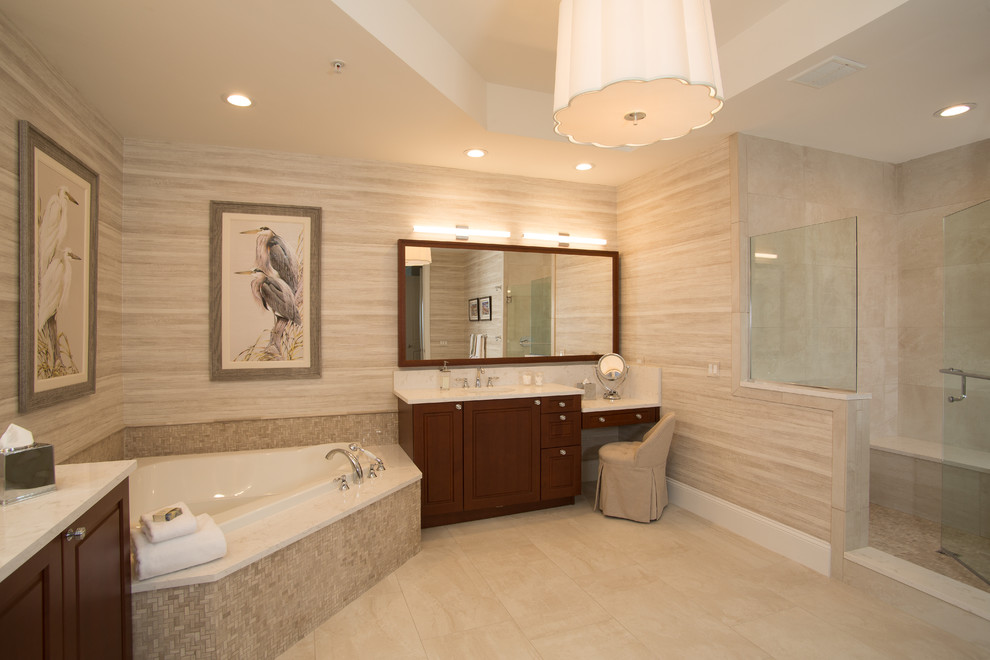 This is an example of a large transitional master bathroom in Jacksonville with raised-panel cabinets, dark wood cabinets, a corner tub, a double shower, beige tile, porcelain tile, beige walls, travertine floors, an integrated sink, quartzite benchtops, beige floor, a hinged shower door and white benchtops.