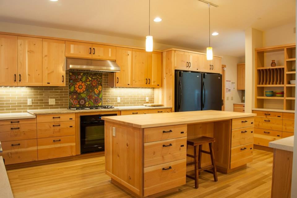 Photo of an arts and crafts l-shaped eat-in kitchen in Seattle with an undermount sink, recessed-panel cabinets, light wood cabinets, quartz benchtops, brown splashback, subway tile splashback, black appliances, light hardwood floors, with island and beige floor.