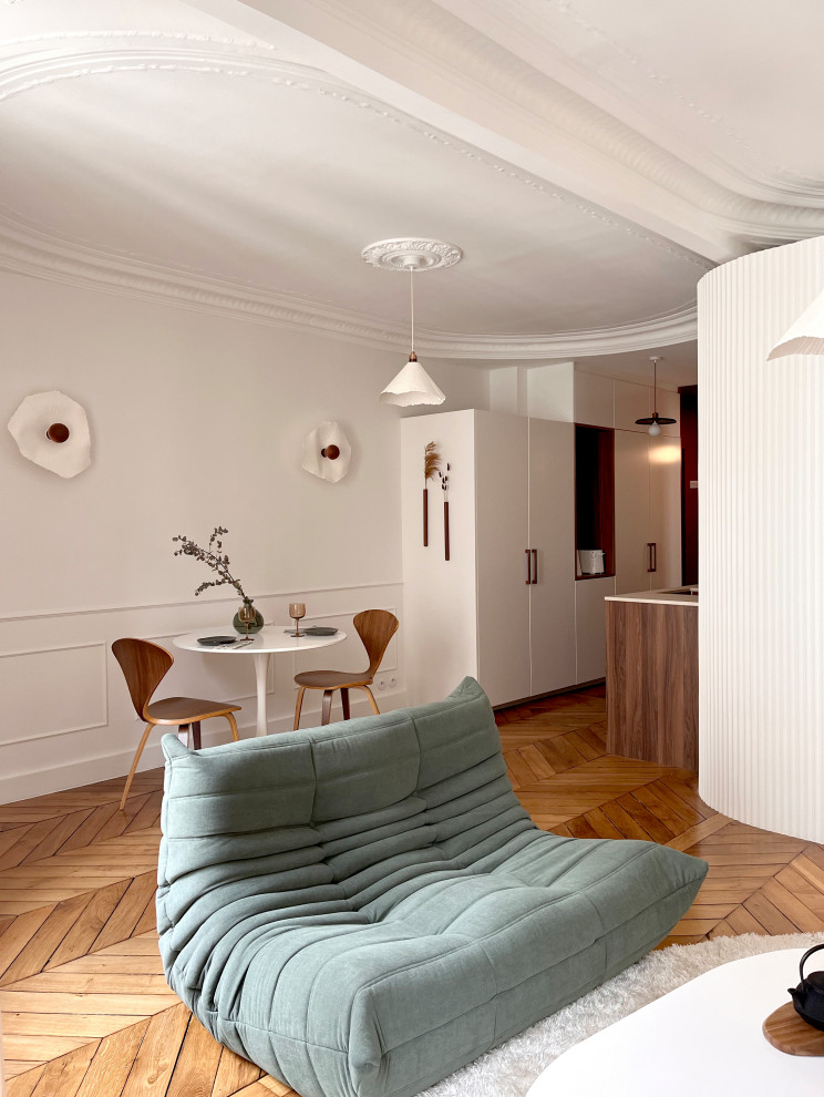 Small transitional open plan dining in Paris with white walls, light hardwood floors and decorative wall panelling.