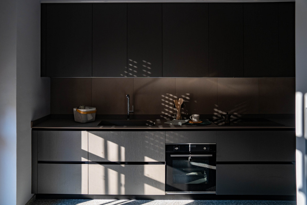 Photo of a mid-sized contemporary single-wall separate kitchen in Turin with flat-panel cabinets, grey cabinets, grey splashback and brown benchtop.