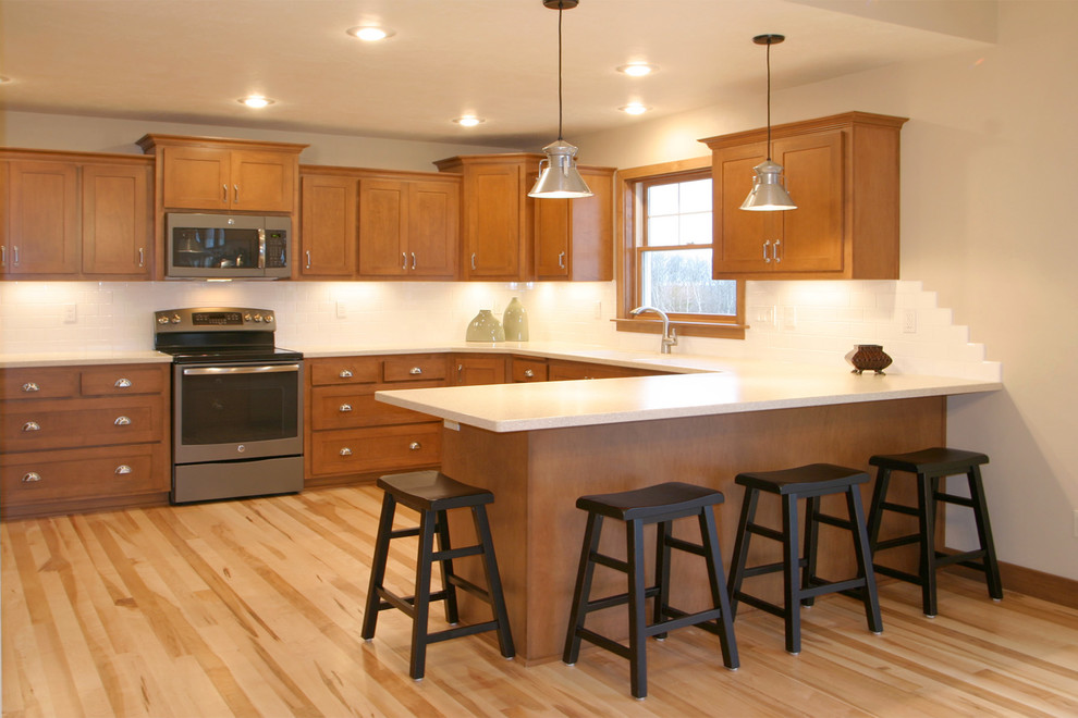 Eat-in kitchen - mid-sized transitional u-shaped light wood floor and beige floor eat-in kitchen idea with an integrated sink, shaker cabinets, medium tone wood cabinets, quartz countertops, white backsplash, subway tile backsplash, stainless steel appliances and a peninsula