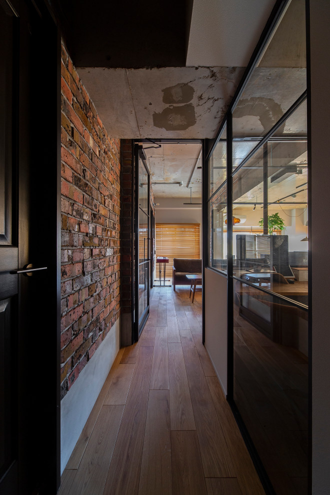 Inspiration for an industrial hallway in Osaka with multi-coloured walls, medium hardwood floors, brown floor, exposed beam and brick walls.