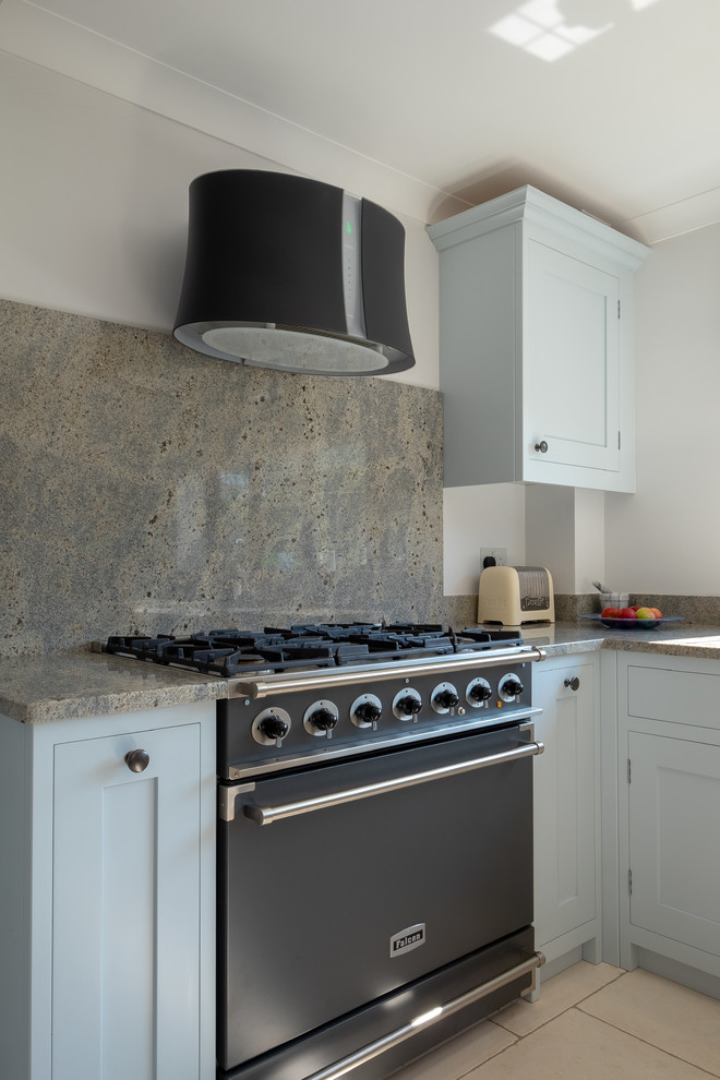 Photo of a mid-sized contemporary l-shaped separate kitchen in Hampshire with a farmhouse sink, shaker cabinets, blue cabinets, granite benchtops, multi-coloured splashback, stone slab splashback, black appliances, limestone floors, multi-coloured floor and multi-coloured benchtop.