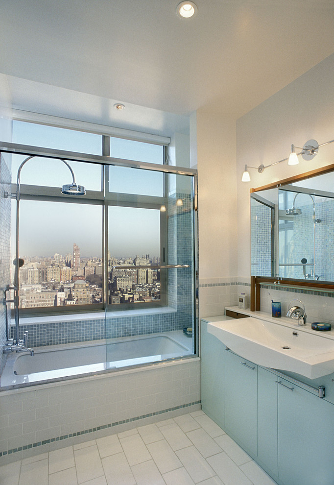 Contemporary bathroom in New York with subway tile and blue cabinets.