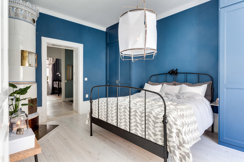 Mid-sized scandinavian master bedroom in Stockholm with blue walls, light hardwood floors and no fireplace.