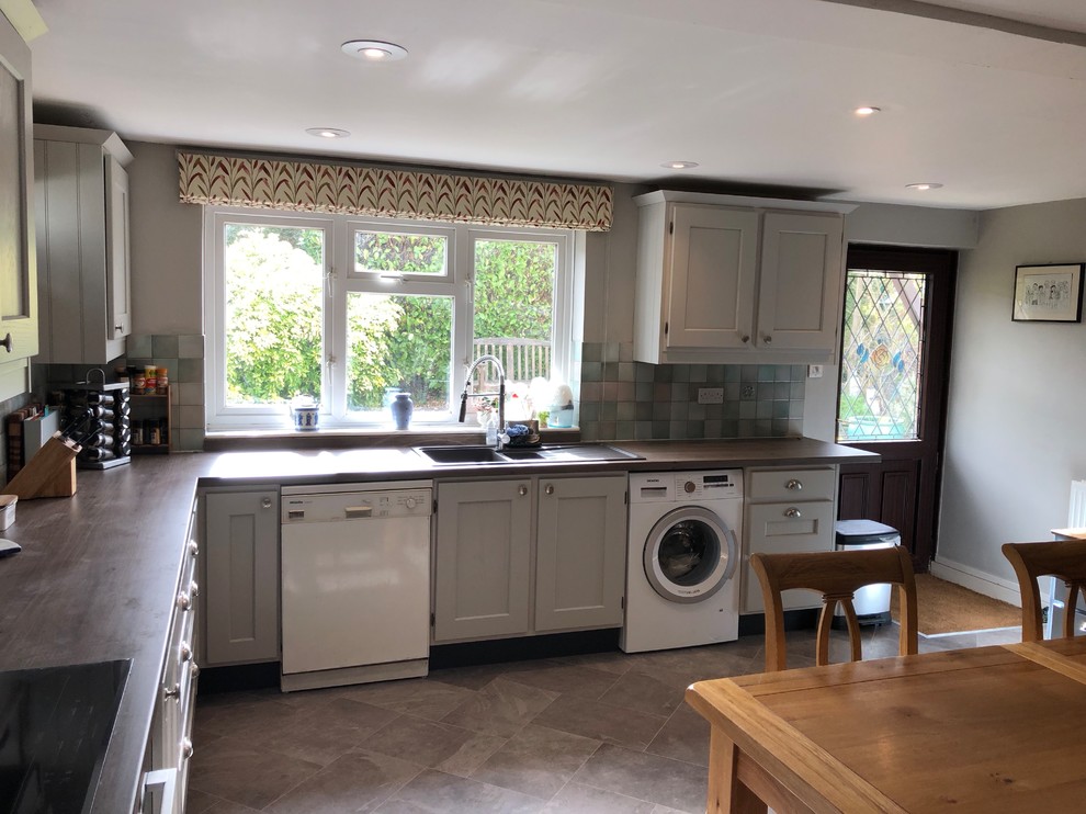 Country kitchen in Oxfordshire with a drop-in sink, shaker cabinets, grey cabinets, laminate benchtops, vinyl floors, grey floor and brown benchtop.