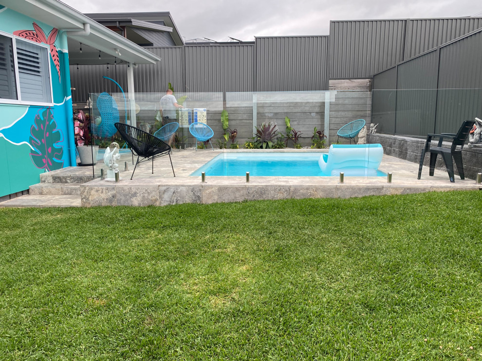 Mid-sized beach style backyard rectangular pool in Wollongong with natural stone pavers.