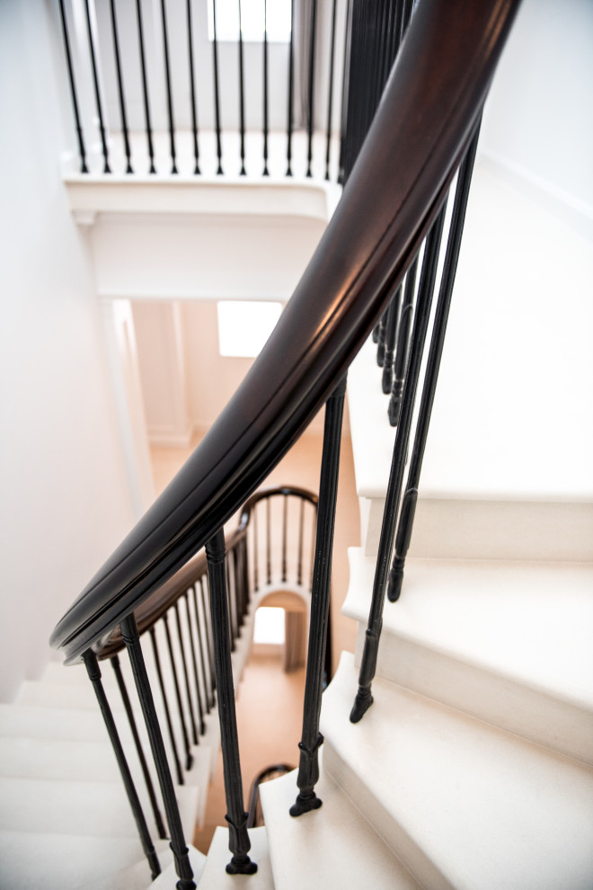 ロンドンにあるトラディショナルスタイルのおしゃれな折り返し階段 (ライムストーンの蹴込み板、金属の手すり) の写真
