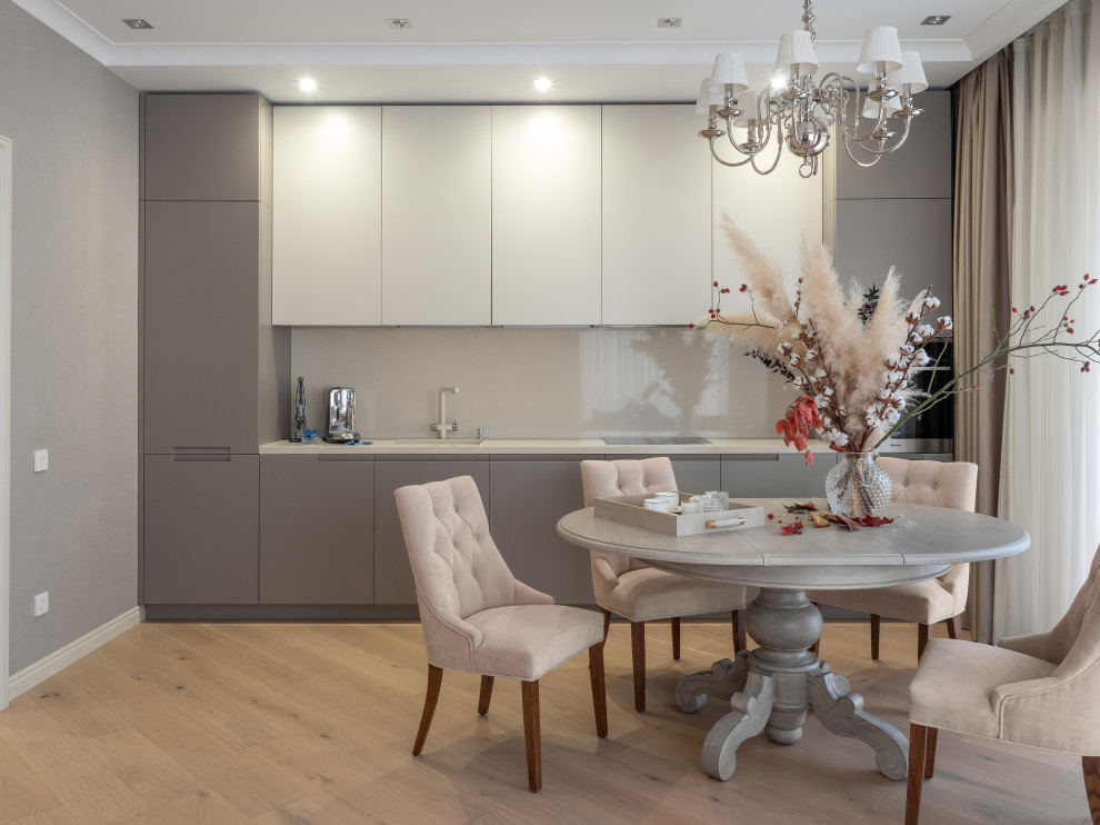 Transitional single-wall eat-in kitchen in Other with flat-panel cabinets, grey cabinets, glass sheet splashback, light hardwood floors, no island, beige floor and white benchtop.