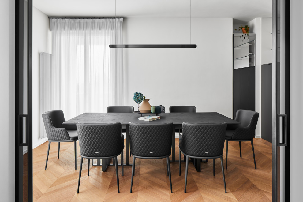 Design ideas for a contemporary dining room in Milan with white walls and light hardwood floors.
