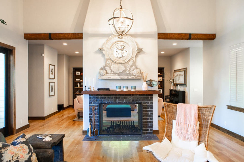 Large eclectic open concept medium tone wood floor, brown floor and exposed beam living room photo in Portland with white walls, a two-sided fireplace and a stone fireplace