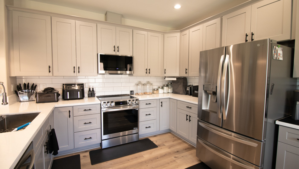 Example of a large minimalist u-shaped laminate floor, beige floor and coffered ceiling eat-in kitchen design in Phoenix with a single-bowl sink, shaker cabinets, gray cabinets, quartz countertops, white backsplash, subway tile backsplash, stainless steel appliances, a peninsula and white countertops